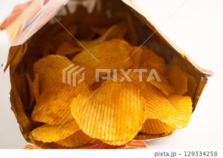Potato chips, delicious BBQ seasoning spicy for crips, thin slice deep fried snack fast food in open bag. 129334258