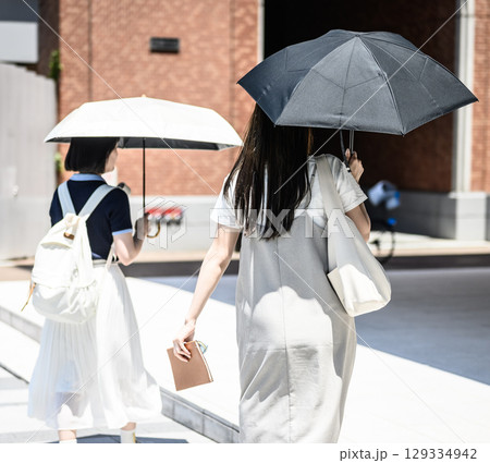 日傘をさして歩く女子学生二人の後ろ姿 日傘をさして歩く女子学生二人の後ろ姿 129334942