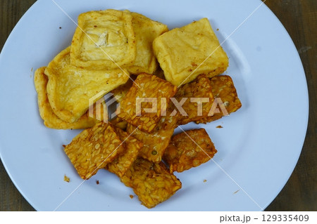 A plate of Indonesian fried snacks, including golden-brown fried tofu and crispy fried tempeh, showcasing the popular local side dishes. A plate of Indonesian fried snacks, including golden-brown fried tofu and crispy fried tempeh, showcasing the popular local side dishes. 129335409