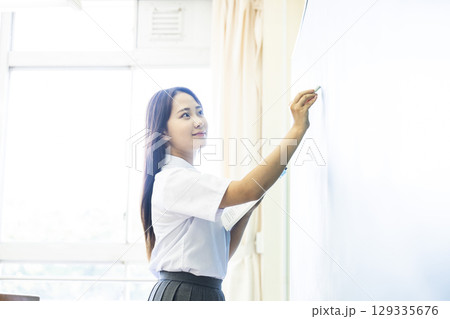 黒板に答えを書く女子高生 129335676