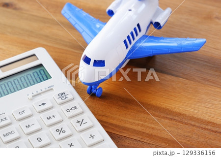 電卓と飛行機 - 高騰する航空券代と、高騰する旅行代金のイメージ 電卓と飛行機 - 高騰する航空券代と、高騰する旅行代金のイメージ 129336156