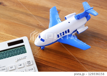 電卓と飛行機 - 高騰する航空券代と、高騰する旅行代金のイメージ 電卓と飛行機 - 高騰する航空券代と、高騰する旅行代金のイメージ 129336158