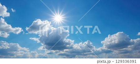 Clear Blue Sky with Bright Sun Over Fluffy White Clouds 129336391