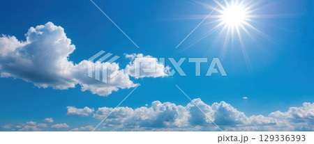 Bright Blue Sky with Fluffy Clouds and Glowing Sunlight 129336393
