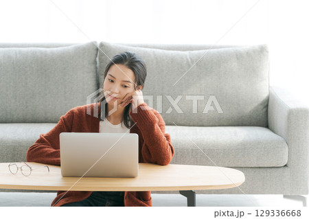 リビングでパソコンを操作する女性 129336668