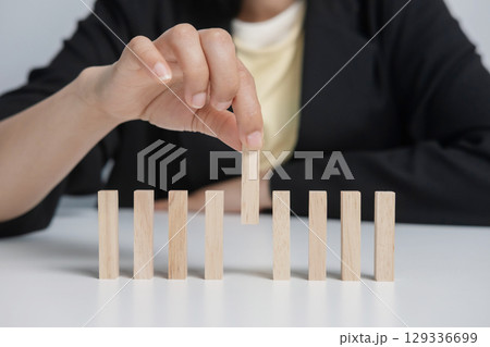 A businesswoman picks a wooden stick from the group. 129336699
