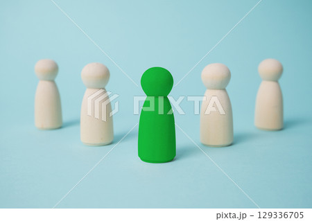 Green leads others from other wooden dolls on blue background. Green leads others from other wooden dolls on blue background. 129336705