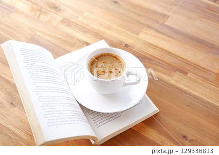 コーヒーを飲みながら、のんびりペーパーバック（洋書）を読んでいるイメージ 129336813