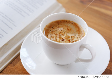 コーヒーを飲みながら、のんびりペーパーバック（洋書）を読んでいるイメージ 129336828