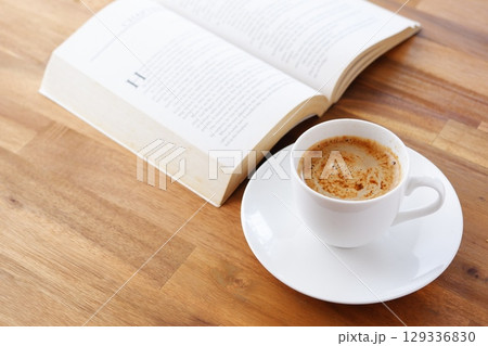 コーヒーを飲みながら、のんびりペーパーバック（洋書）を読んでいるイメージ 129336830