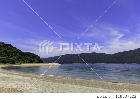 砂浜から望むムーンビーチ井野浦と防波堤、遠くに見える風車の夏景色 129337222