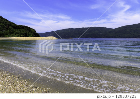 砂浜から望むムーンビーチ井野浦と防波堤、遠くに見える風車の夏景色 129337225