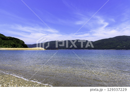 砂浜から望むムーンビーチ井野浦と防波堤、遠くに見える風車の夏景色 129337229