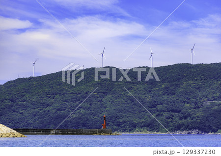 砂浜から望むムーンビーチ井野浦と防波堤、遠くに見える風車の夏景色 129337230