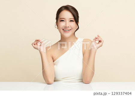 A beautiful young Asian woman with clean, fresh skin against a beige background. Skincare, facial treatment, cosmetology, beauty, and spa. An elegant portrait of an Asian woman. A beautiful young Asian woman with clean, fresh skin against a beige background. Skincare, facial treatment, cosmetology, beauty, and spa. An elegant portrait of an Asian woman. 129337404
