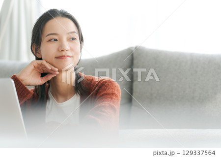 リビングでパソコンを操作する女性 129337564