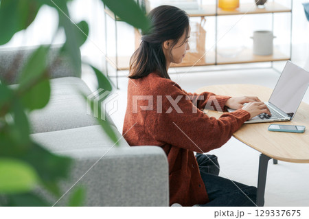 リビングでパソコンを操作する女性 129337675
