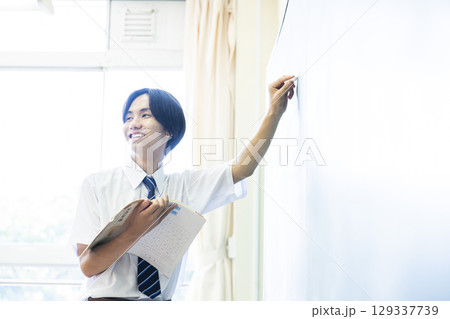 黒板の前で発表する男子中学生 黒板の前で発表する男子中学生 129337739