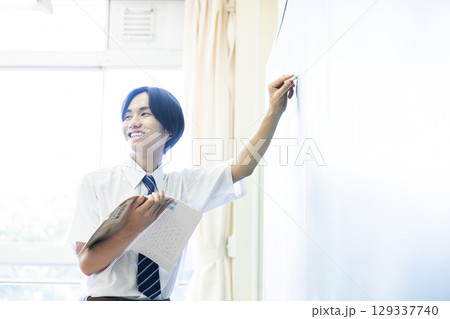 黒板の前で発表する男子中学生 129337740