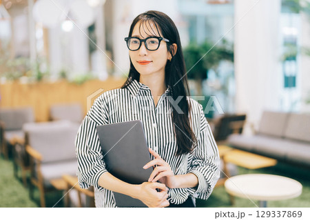 オフィスでパソコンを持ち歩くビジネスウーマン 129337869