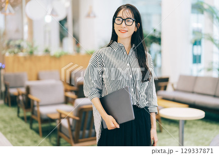 オフィスでパソコンを持ち歩くビジネスウーマン 129337871