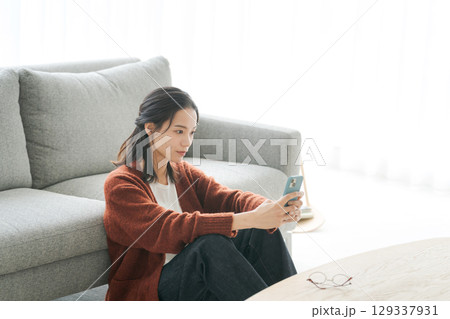 リビングでスマホを見る若い女性 リビングでスマホを見る若い女性 129337931