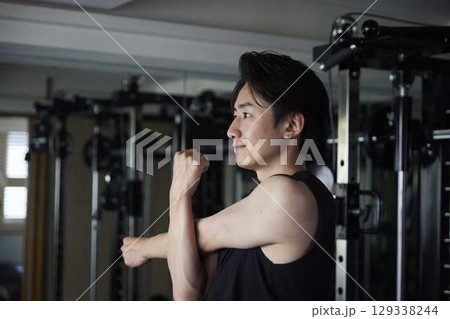 トレーニング前に肩まわりを伸ばす若い男性 トレーニング前に肩まわりを伸ばす若い男性 129338244