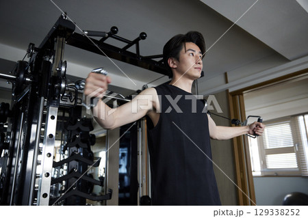 フィットネスジムで筋力トレーニングを行うスポーツウェアを着た若い日本人男性 129338252