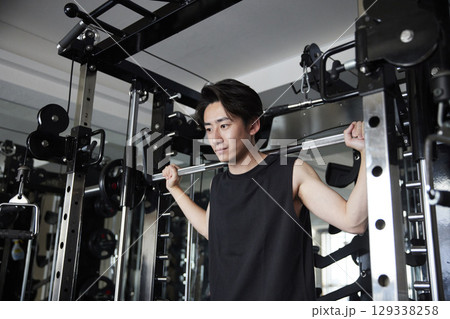 フィットネスジムで筋力トレーニングを行うスポーツウェアを着た若い日本人男性 フィットネスジムで筋力トレーニングを行うスポーツウェアを着た若い日本人男性 129338258