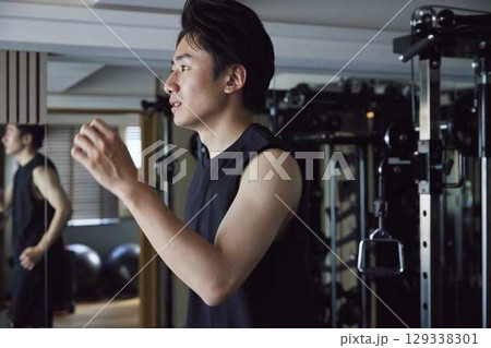 ジムのランニングマシンで持久力を鍛える若い男性 ジムのランニングマシンで持久力を鍛える若い男性 129338301