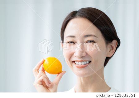 レモンを手に持ってフレッシュな笑顔を見せる透明感のある女性 顔のアップ 129338351