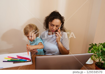 Mother Balancing Work at Home While Attending to Child's Activities Mother Balancing Work at Home While Attending to Child's Activities 129338570
