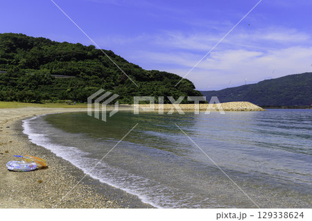 砂浜から望むムーンビーチ井野浦と防波堤、遠くに見える風車の夏景色 129338624