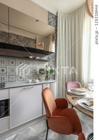 Modern Kitchen Interior with Retro Tiles and Velvet Chairs 129338644