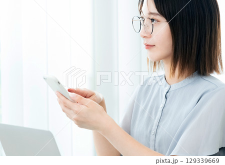 オフィスでスマホを見るビジネスウーマン オフィスでスマホを見るビジネスウーマン 129339669