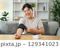 An Asian woman uses a portable blood pressure monitor in her living room. Health awareness concept. 129341023