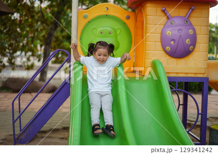 happy toddler baby girl sliding and playing at playground 129341242