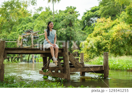 woman resting on edge of wooden jetty 129341255