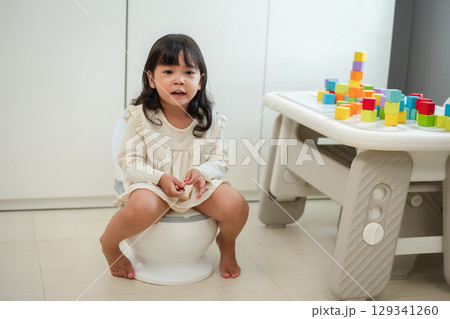 toddler gir learning sit on toilet wc seat at home. child being potty trained and suffering from stomachache and constipation 129341260
