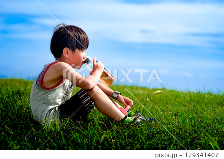 ＜素材＞公園遊び中に水筒のお茶を飲む少年 129341407