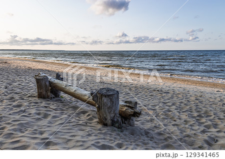 Tranquil Baltic Sea Shore at Sunset with Driftwood Bench and Gentle Waves 129341465