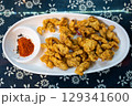 Xiao Shu Rou. Crispy fried pork snacks served on a white platter 129341600