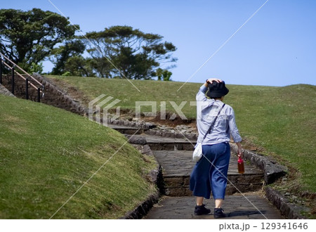 ＜素材＞山の上の遊歩道を散歩する旅行中の女性 129341646