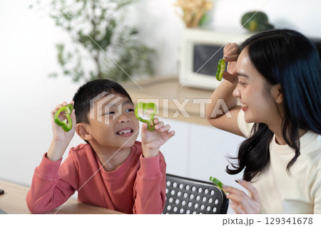 Healthy Cooking Fun: Mother and son enjoying time preparing green bell peppers together 129341678