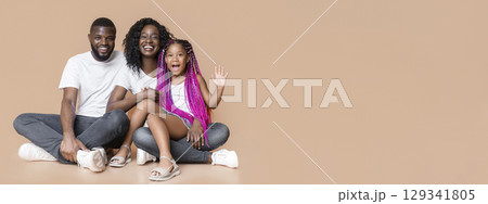 Happy Family Concept. Cheerful Young Afro Parents And Their Little Daughter Hugging And Posing To Camera In Studio Over Yellow Background, Free Space Happy Family Concept. Cheerful Young Afro Parents And Their Little Daughter Hugging And Posing To Camera In Studio Over Yellow Background, Free Space 129341805