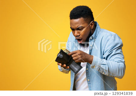 Where's my money. Shocked african american guy holding wallet with dollar cash that will be not enough to cover spendings, yellow studio background. Where's my money. Shocked african american guy holding wallet with dollar cash that will be not enough to cover spendings, yellow studio background. 129341839