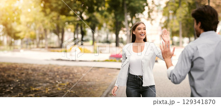 Hello Greeting. Girl Waving Hand Meeting Friend Guy Walking Outdoors In Park. Selective Focus Hello Greeting. Girl Waving Hand Meeting Friend Guy Walking Outdoors In Park. Selective Focus 129341870