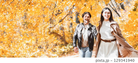 Emotional young man and woman running in sunlight of autumn forest, holding hands Emotional young man and woman running in sunlight of autumn forest, holding hands 129341940