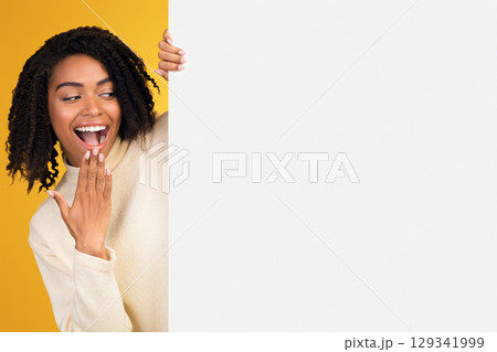 Excited Black Woman Looking Over Copy Space, Hiding Behind Blank Billboard, Peeking Out White Placard Excited Black Woman Looking Over Copy Space, Hiding Behind Blank Billboard, Peeking Out White Placard 129341999