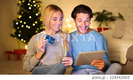 Preparing for Christmas. Happy couple buying gifts online, using tablet and credit card 129342003